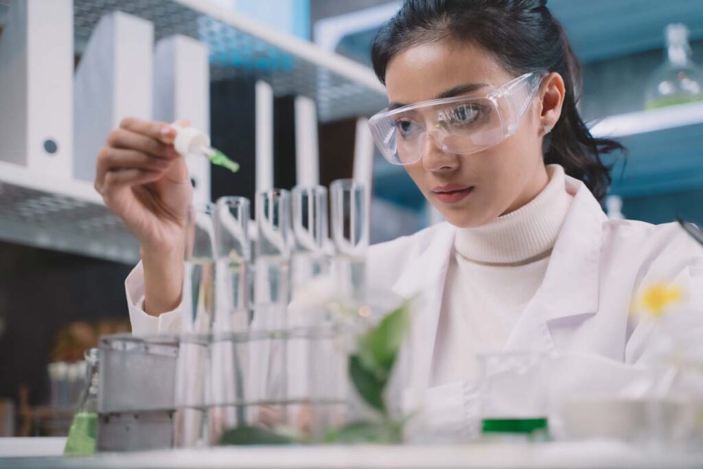A female lab worker putting drops into a test tube, representing recent class actions over preservatives in products.