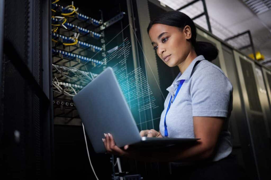 IT worker using a laptop to troubleshoot a problem in a server room, representing the Gas South data breach settlement.