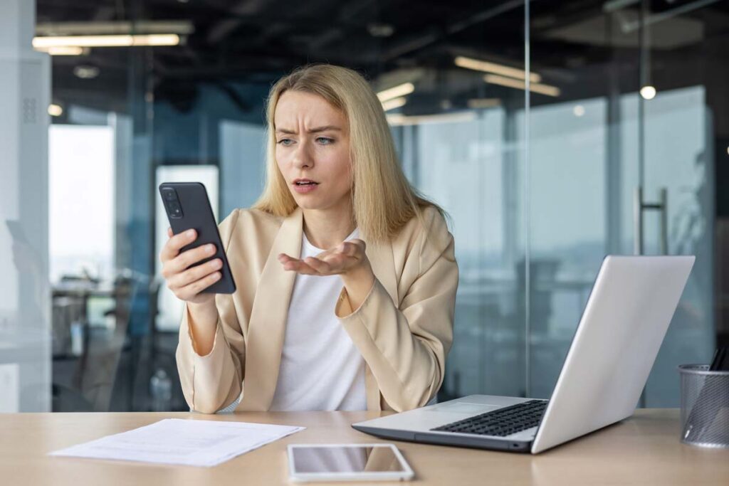 Upset woman looking at a text message on her phone, representing recent TCPA class action lawsuits and settlements.