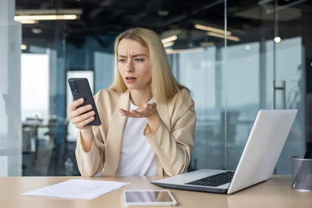 Upset woman looking at a text message on her phone, representing recent TCPA class action lawsuits and settlements.