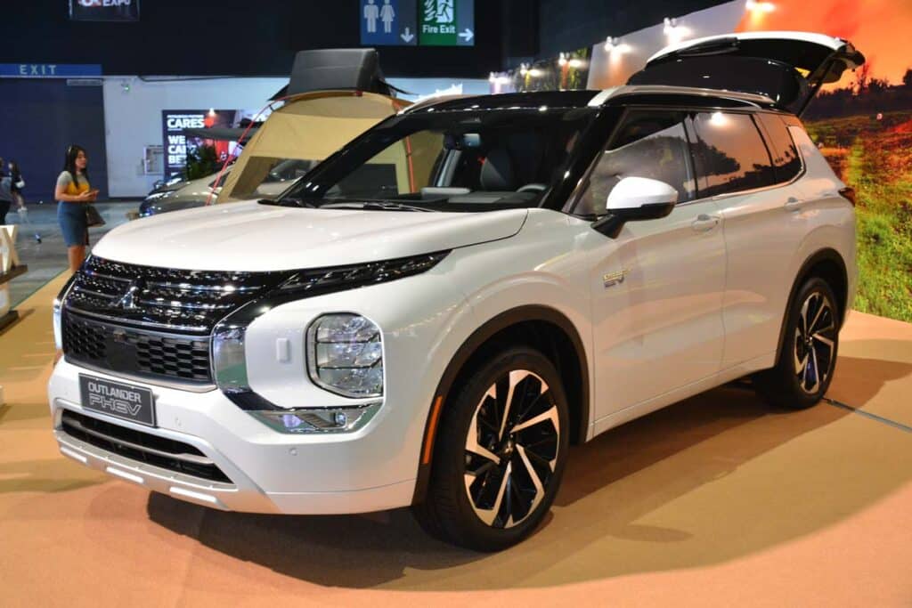 A white Mitsubishi Outlander PHEV at a car show, representing the Mitsubishi class action.
