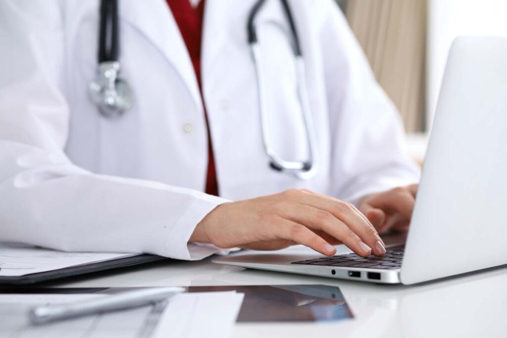 Close up of a doctor typing on a laptop, representing the Massachusetts hospital data beach class action.