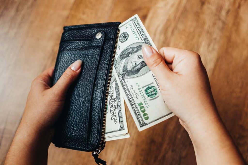 Close up of cash being put into a wallet, representing recent class action rebates.