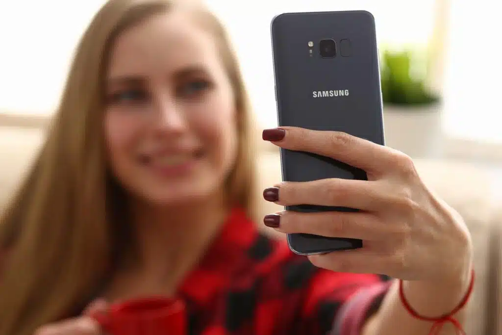 A woman taking a selfie on a Samsung phone, representing Samsung biometric data arbitration.