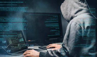 Close up of a hooded hacker using a computer, representing the Webster Bank data breach settlement.