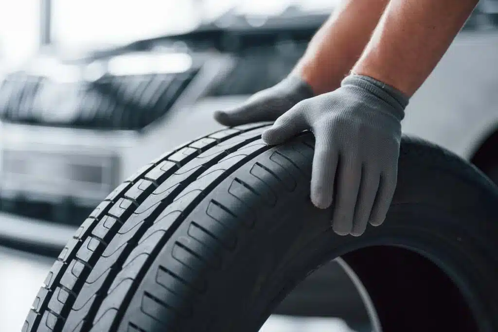 Close up of a mechanic with his hands on a new tire, representing the tire class action.