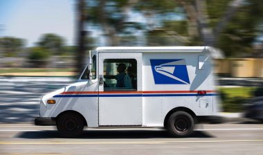 A USPS worker driving a USPS vehicle, representing the USPS class action lawsuit.