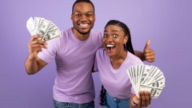 An excited couple holding cash, representing recent settlement payouts to consumers.