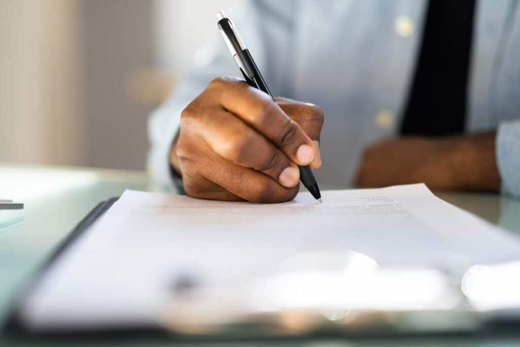 Close up of African American male filling out a job application, representing the Vee Pak class action lawsuit settlement.
