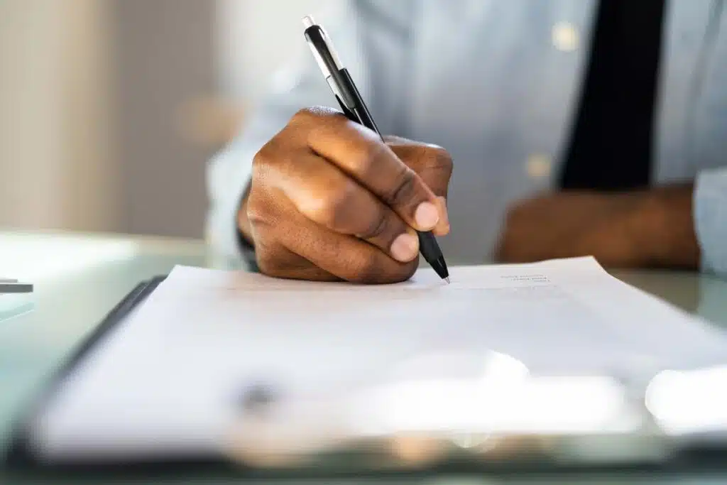 Close up of African American male filling out a job application, representing the Vee Pak class action lawsuit settlement.
