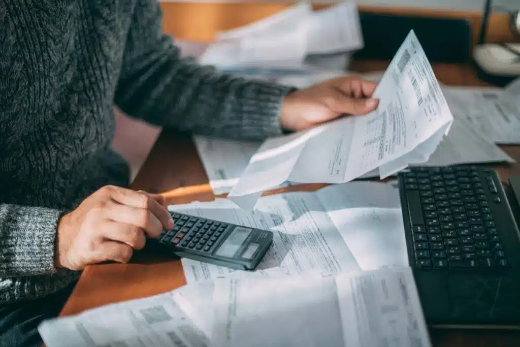 Close up of a man calculating interest of a bill with a calculator, representing the Calyx Energy settlement.