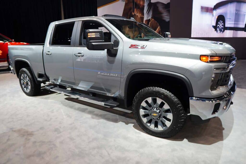 A 2024 silver Chevrolet Silverado 2500 at a car show, representing the GM truck recall over a potential tailgate unlatch issue.