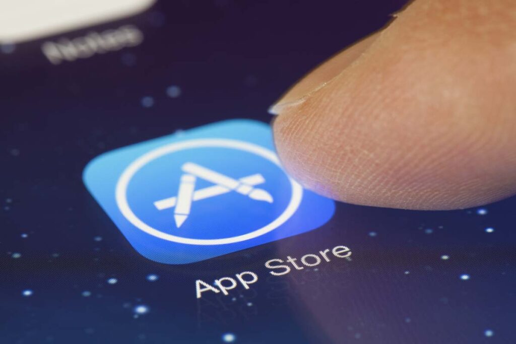 Close up of finger selecting Apple App store icon on smartphone display, representing the Apple iPhone web apps antitrust lawsuit.