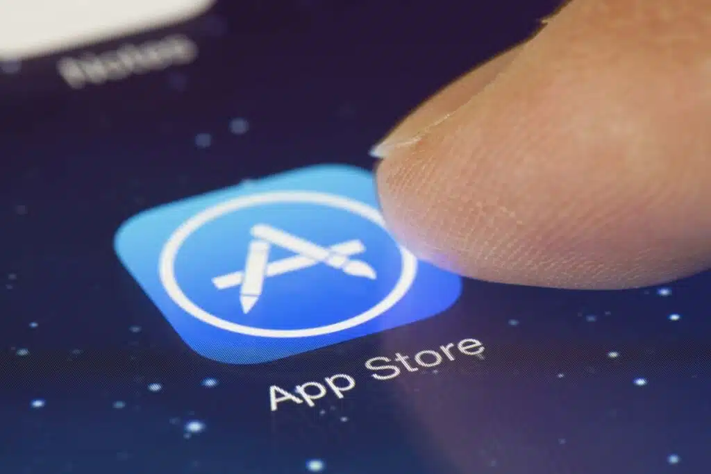 Close up of finger selecting Apple App store icon on smartphone display, representing the Apple iPhone web apps antitrust lawsuit.