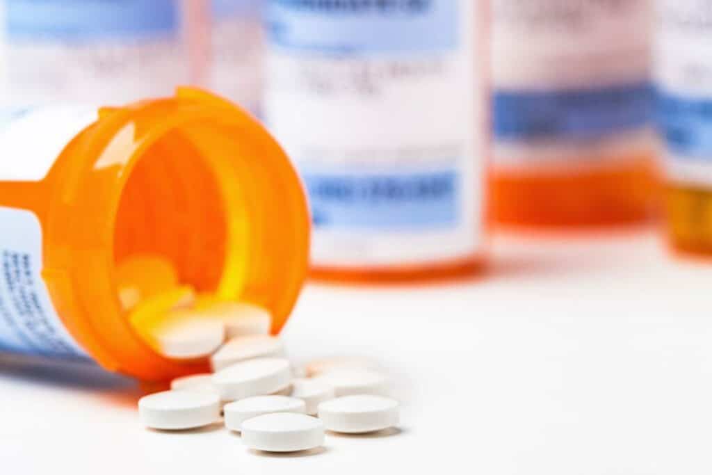 Closeup of pills spilling out of a pill bottle, representing the generic drugs direct purchasers class action settlement.