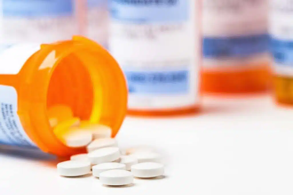 Closeup of pills spilling out of a pill bottle, representing the generic drugs direct purchasers class action settlement.