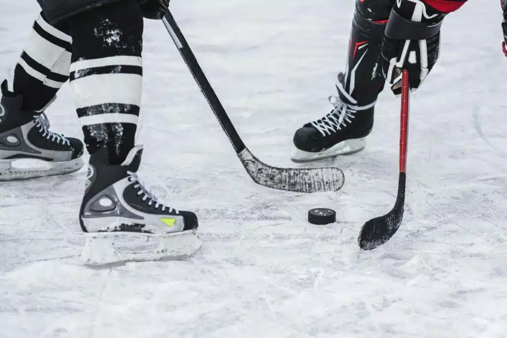 Close up of hockey players with a hockey puck, representing the NHL class action lawsuit.