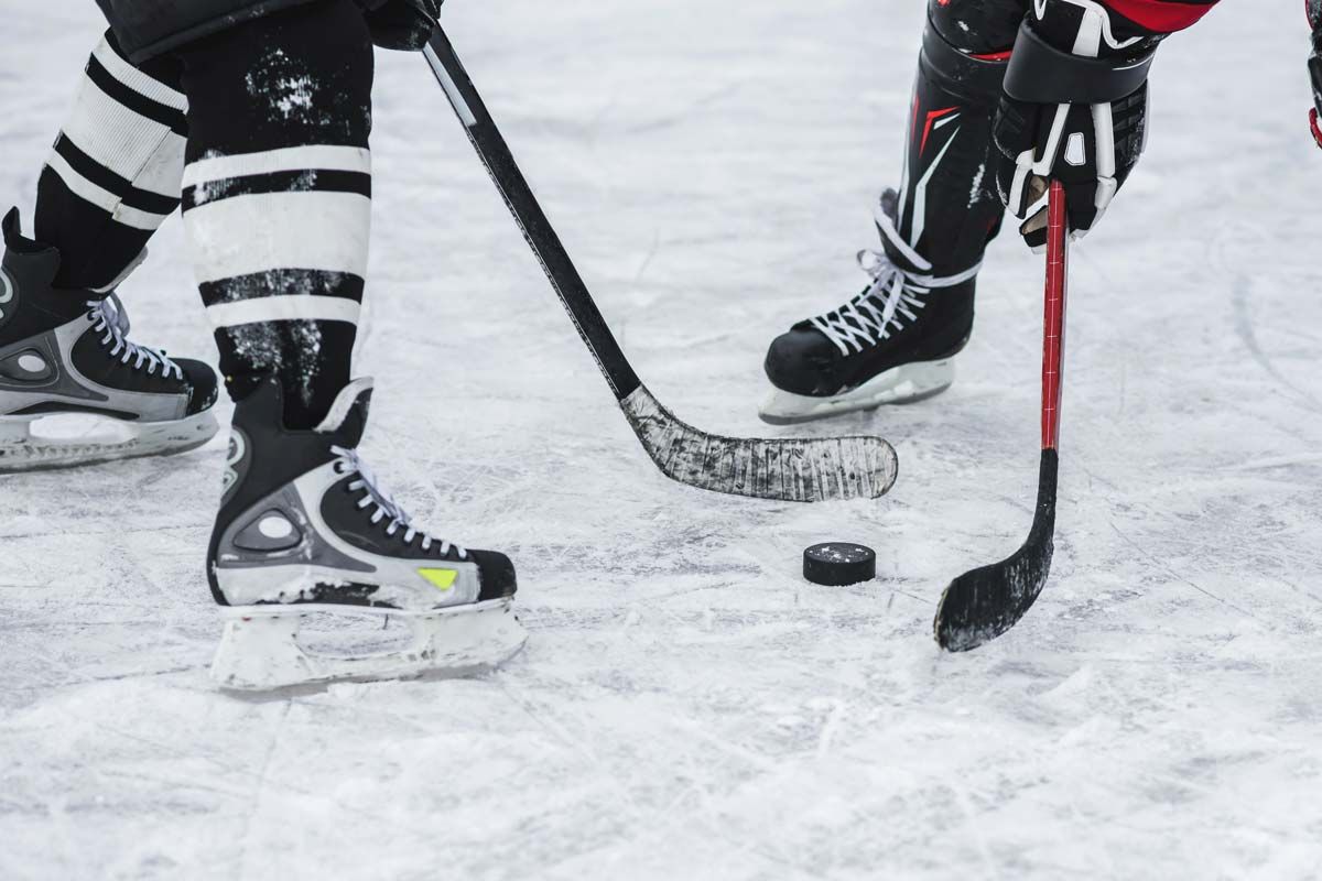 Close up of hockey players with a hockey puck, representing the NHL class action lawsuit.
