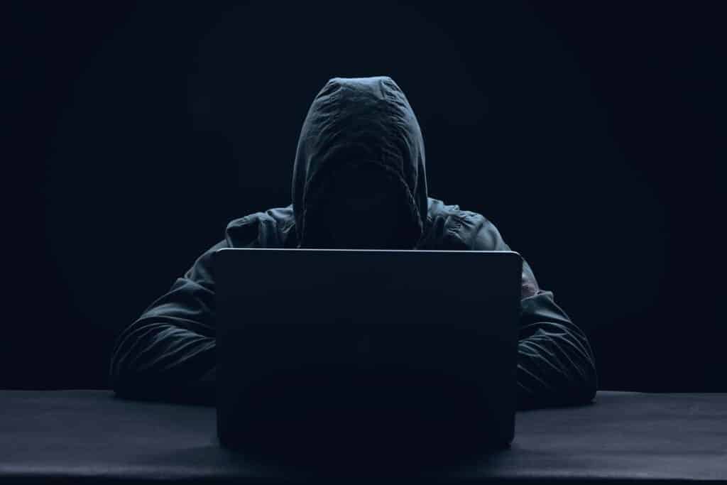A hooded hacker using a laptop, representing the Integris Health class action.