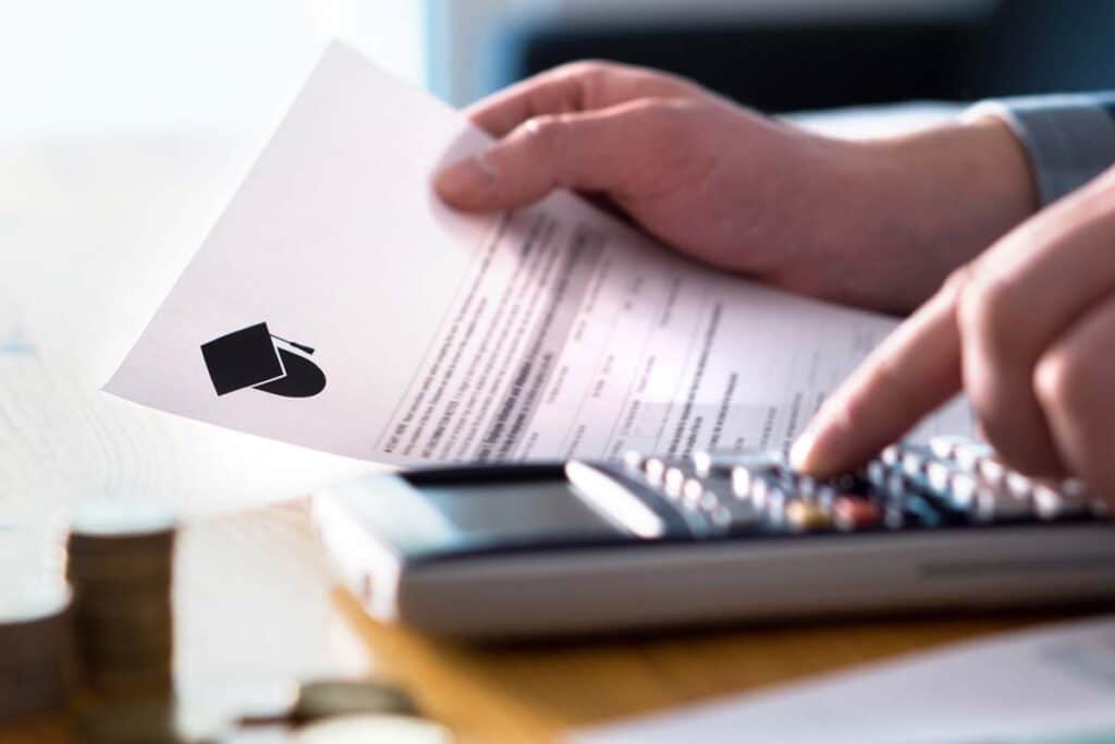 Close up of a man calculating tuition on a calculator, representing the American University tuition settlement.