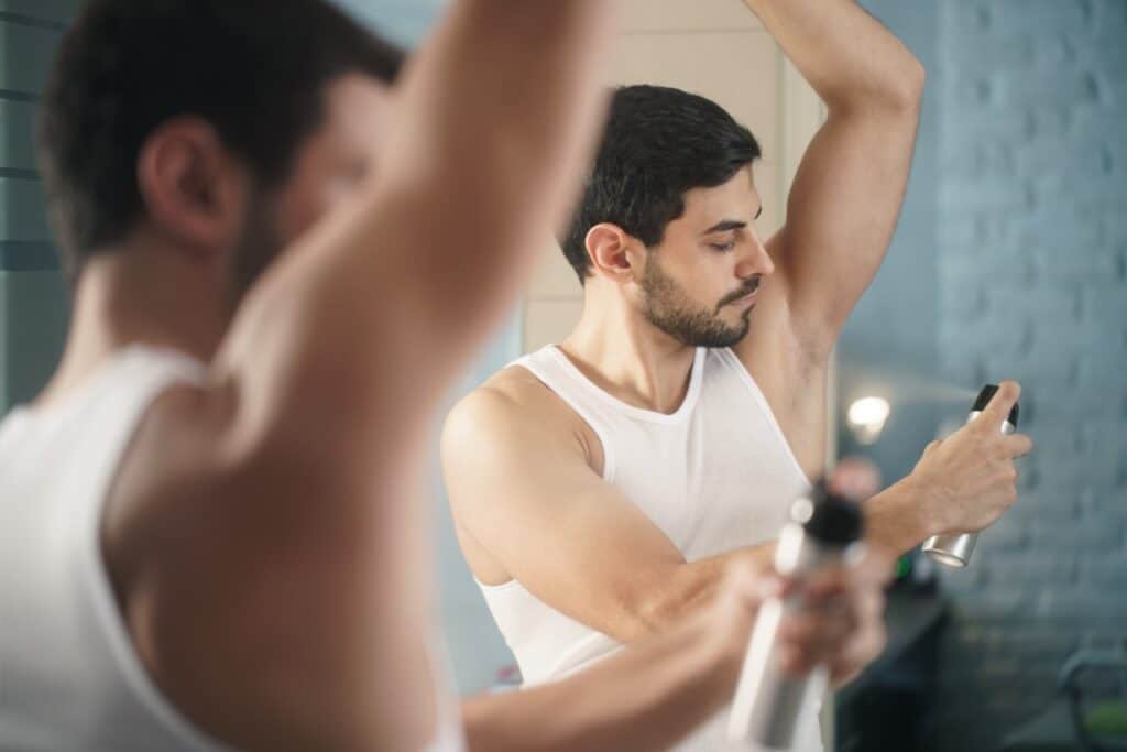 Man putting on spray deodorant.