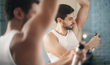 Man putting on spray deodorant.