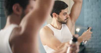 Man putting on spray deodorant.