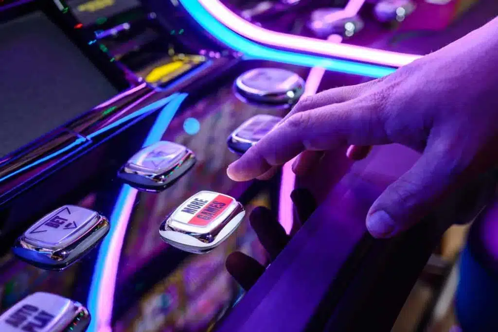 Close up of a males hands pushing a button on a slot machine, representing the Crystal Bay Casino data breach settlement.