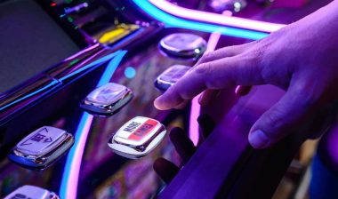 Close up of a males hands pushing a button on a slot machine, representing the Crystal Bay Casino data breach settlement.