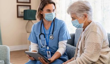 Home health nurse using a tablet with a patient, representing the Personal Touch data breach settlement.
