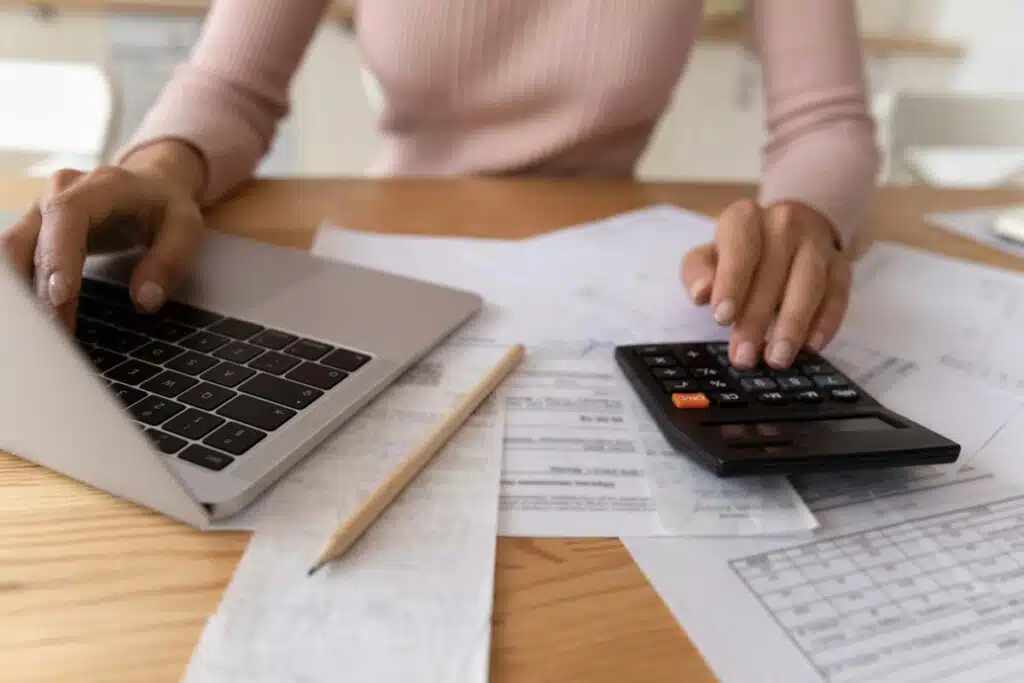 Close up of a businesswoman using a laptop and calculator, representing the First American Payment Systems FTC settlement.