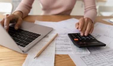 Close up of a businesswoman using a laptop and calculator, representing the First American Payment Systems FTC settlement.