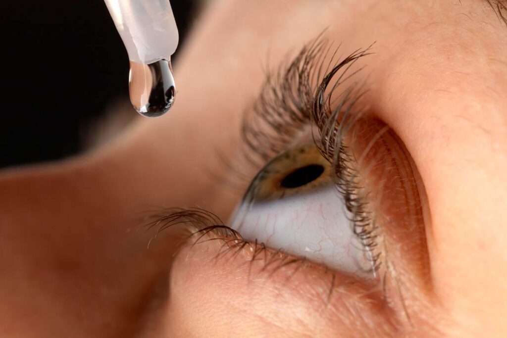 Close up of a woman putting eye drops into her eye, representing the Walmart Ezricare artificial tears  bacteria class action.