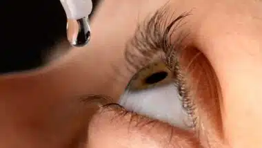 Close up of a woman putting eye drops into her eye, representing the Walmart Ezricare class action.