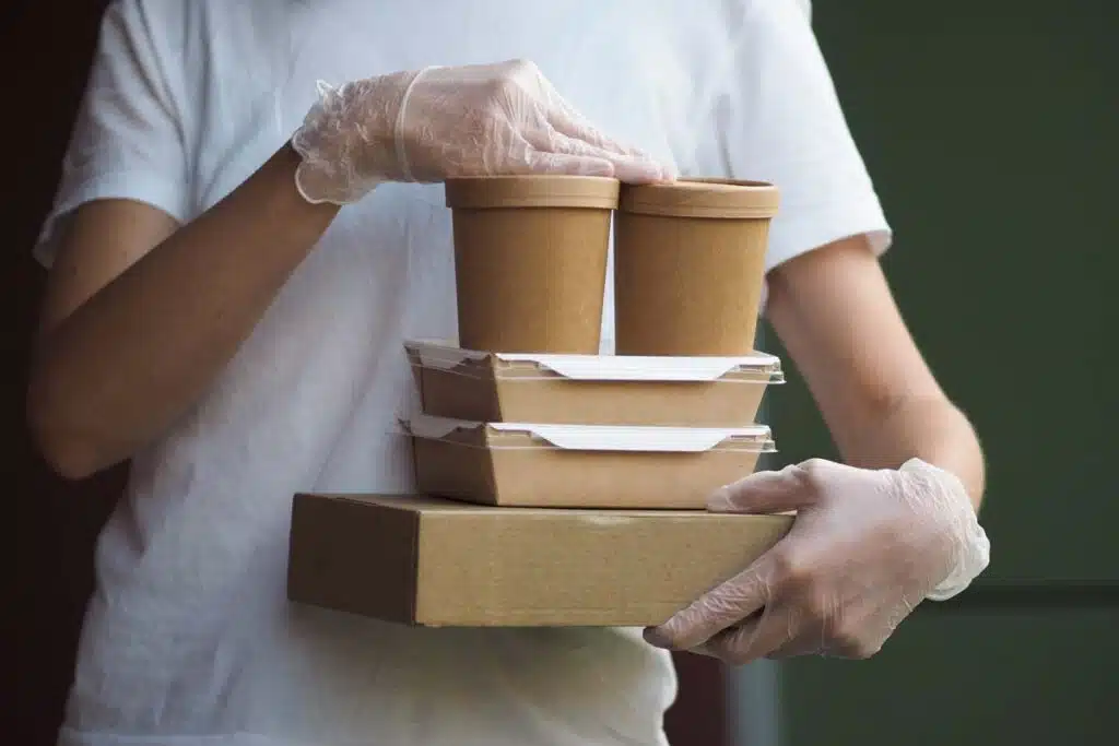 Close up of a worker carrying paperboard take out containers, representing the PFAS food packaging agreement.