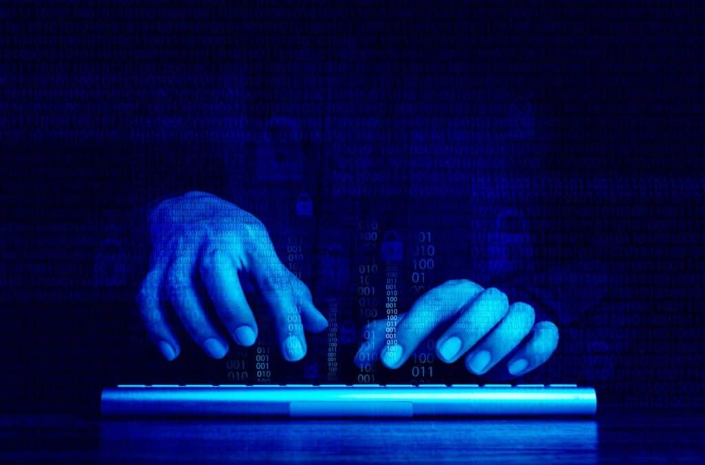 Closeup of a hacker typing on a keyboard with a binary code overlay, representing the Southland Holdings data breach class action lawsuit settlement.