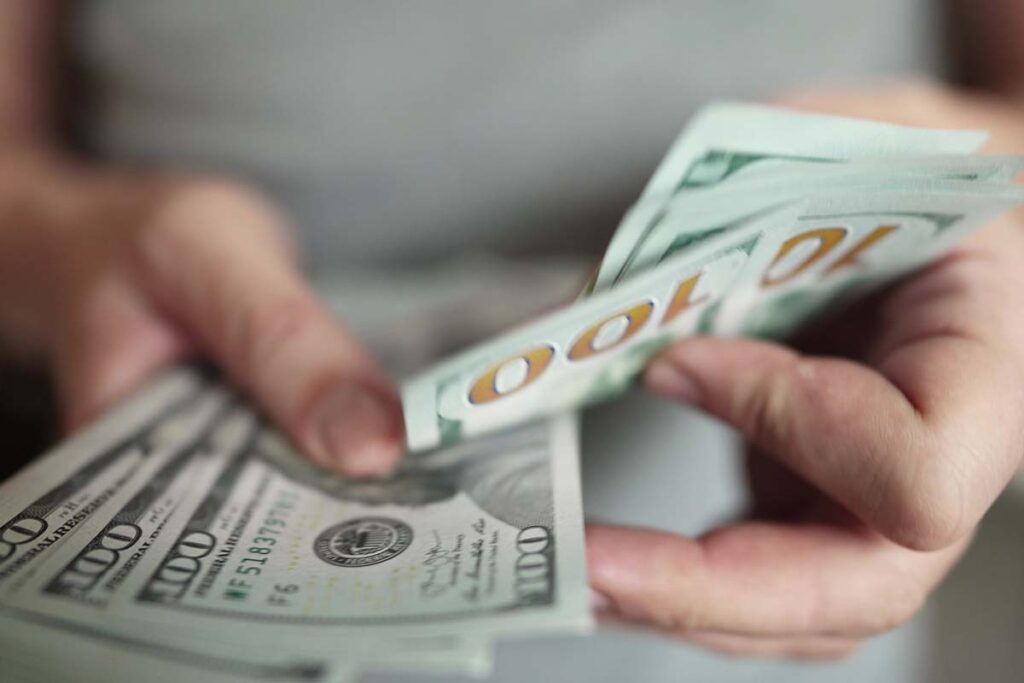 Close up of a woman counting U.S. cash, representing recent class action rebates.
