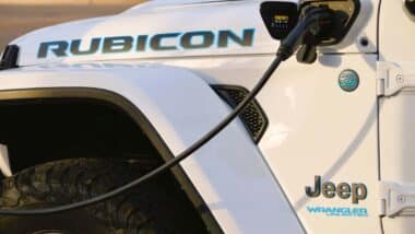 Close up of a white Jeep Wrangler 4xe plug-in hybrid plugged into a charger, representing the Jeep class action.