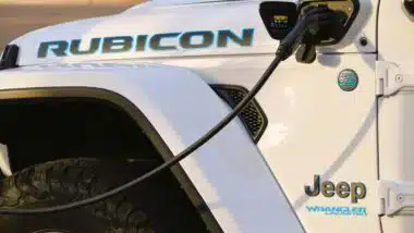 Close up of a white Jeep Wrangler 4xe plug-in hybrid plugged into a charger, representing the Jeep class action.