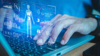 Close up of a medical professional typing on a laptop with a patient data concept overlay, representing the Change Health Care cyberattack.