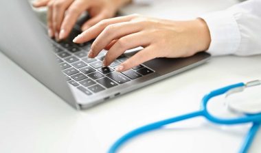 Close up of a female doctor typing on a laptop, representing the Avem Health Partners data breach settlement.