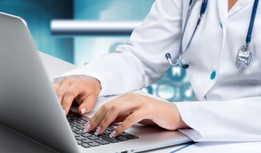 Close up of a doctor typing on a laptop, representing the Lamoille Health Partners data breach settlement.