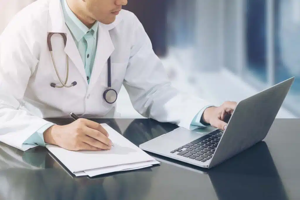 Closeup of a doctor working on a laptop, representing the Tennessee Orthopaedic Clinics class action settlement.