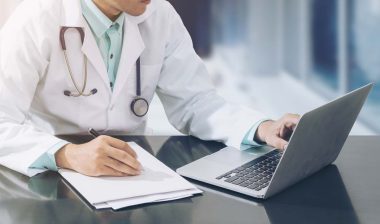 Close up of a doctor working on a laptop, representing the Tennessee Orthopaedic Clinics settlement.