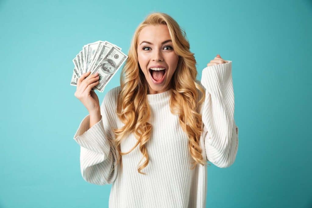 An excited woman holding cash, representing recent settlement checks in the mail.