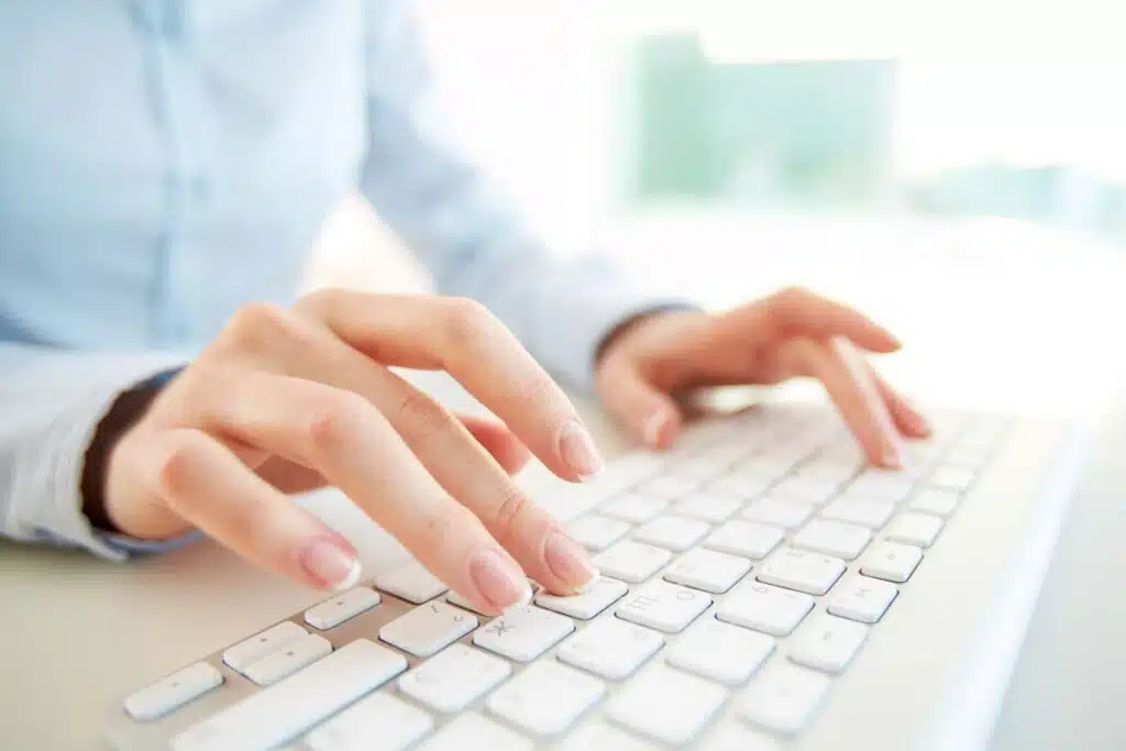 Close up of a woman typing on a keyboard for a background check, representing the SH Group settlement.
