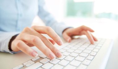Close up of a woman typing on a keyboard for a background check, representing the SH Group settlement.