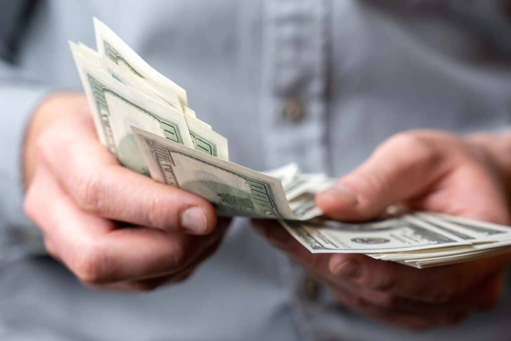 Close up of a man holding US cash, representing FTC refunds in March 2024.
