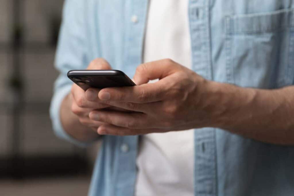 Close up of a mans hands using a smartphone, representing the NFL texts class action.