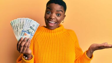 A happy woman holding cash, representing class action settlement payments.